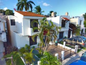 a white house with palm trees in front of it at Cómoda casa céntrica con alberca privada en Cancún in Cancún