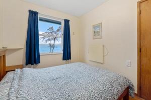 a bedroom with a bed and a window at The Blue Bach - Lake Rotoiti Holiday Home in Rotoiti