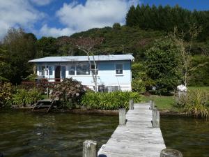 Rotoiti的住宿－The Blue Bach - Lake Rotoiti Holiday Home，水体旁的码头上的房子
