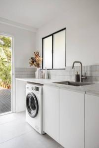a white kitchen with a washing machine and a sink at The Aura House in Tweed Heads