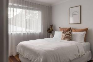 een slaapkamer met een wit bed en een raam bij The Aura House in Tweed Heads