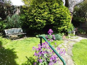 a garden with a bench and some purple flowers at Josie's Cottage in Hobart