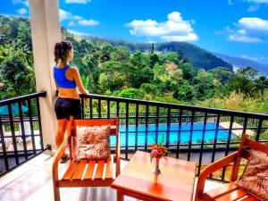 a woman standing on a balcony looking out at a pool at The Grand Hills in Kandy