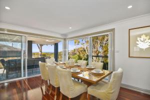 a dining room with a table and chairs and windows at Diamond Head Manor in Budgewoi