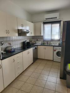 uma cozinha com armários brancos e bancadas pretas em Villa Gracia em Ayia Napa