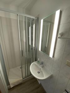 a white bathroom with a shower and a sink at Pension Grunwald in Sehnde