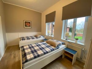 two beds in a room with two windows at Pension Grunwald in Sehnde