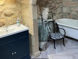 a bathroom with a sink and a tub and a chair at Bird In Bush Elsdon in Elsdon