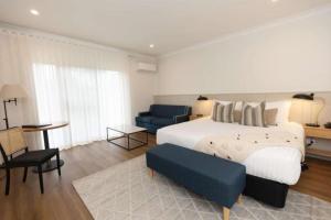 1 dormitorio con 1 cama grande y 1 silla azul en Clare Country Club, en Clare