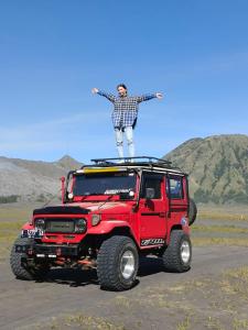 Ein Mann steht auf einem roten Jeep in der Unterkunft The Arya guest house in Gilimanuk