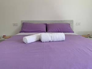 a purple bed with two white towels on it at LA CROISETTE Agriturismo - Farmhouse in Dorgali