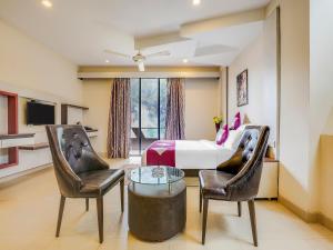 a bedroom with a bed and two chairs and a table at Grandeur De Sanchi- Luxury Beach Resort & Spa in Calangute