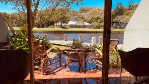 a patio with a table and chairs and a lake at Beachside Resort Lagoon Rooms with Garden Patio in Coffs Harbour