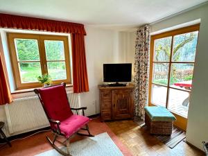 a living room with a red chair and a tv at Auszeitshäusel ideal für Naturfreunde und Wanderer in Marktschellenberg