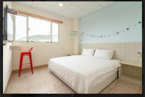 1 dormitorio con cama blanca y taburete rojo en 馬祖北竿達露岸海景民宿 可電洽, en Beigan