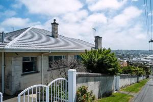 a house with a tile roof and a fence at Seaview Cottage in Oamaru