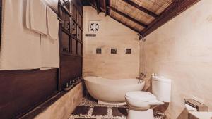 a bathroom with a toilet and a bath tub at Kayu Manise Villa Bedugul in Tabanan