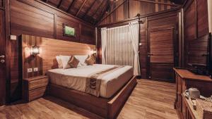 a bedroom with a bed in a room with wooden walls at Kayu Manise Villa Bedugul in Tabanan