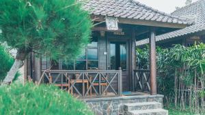 a house with a porch and a palm tree at Kayu Manise Villa Bedugul in Tabanan