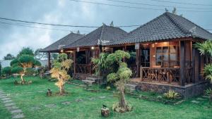 a wooden house with a garden in front of it at Kayu Manise Villa Bedugul in Tabanan