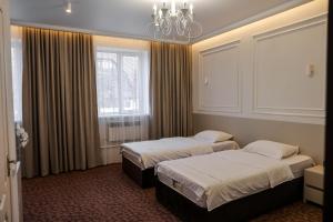 Habitación de hotel con 2 camas y lámpara de araña. en Grand Hotel, en Bishkek