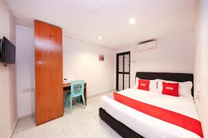 una camera con letto, scrivania e TV di OYO 1132 Azimaju Guesthouse a Malacca