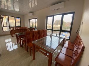 uma sala de jantar com mesas, cadeiras e janelas em Rosa Quỳnh Anh em Haiphong