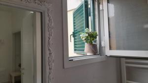 a window with a mirror and a vase with flowers in it at B&B Casa Alinella, Happy and Sustainable Hospitality in Taranto