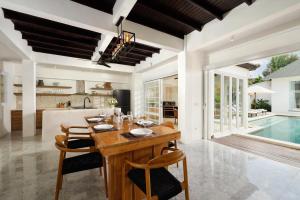 a dining room with a table and chairs and a pool at Villa Swarna by Nakula in Seminyak