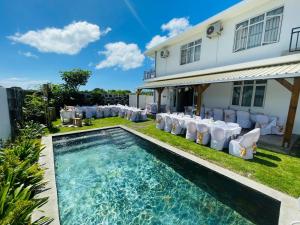 a backyard with a swimming pool and chairs and a house at Red Fody Villa in Triolet