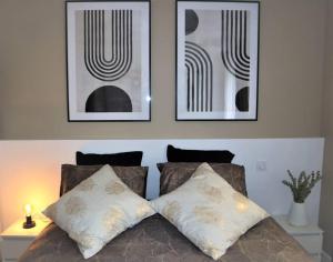 a bed with two pillows and three pictures on the wall at L'Élégant avec garage, proche Axone, Stellantis in Audincourt
