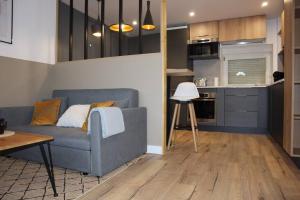 a living room with a blue couch and a kitchen at L'Élégant avec garage, proche Axone, Stellantis in Audincourt