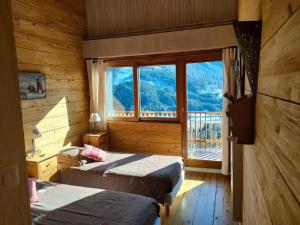 two beds in a room with a large window at Chambres d'hôtes Le Grand Chalet in Valdeblore