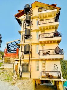 un edificio amarillo con balcones en un lateral en Staynest Mashobra with balcony- A peacefull stay, en Shimla