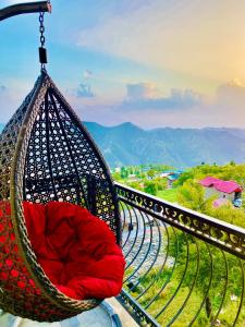 a hammock with a red pillow sitting on a balcony at Staynest Mashobra with balcony- A peacefull stay in Shimla