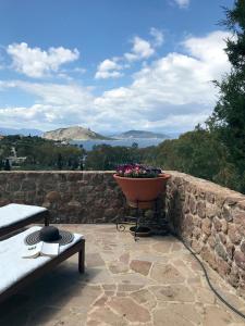 a planter on a stone wall with a pot of flowers at serenity villa Aegina fantastic view near the beach in Aegina Town