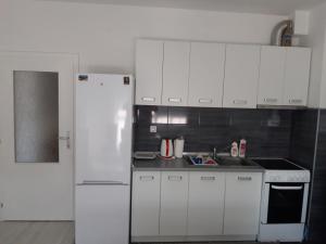 a kitchen with white cabinets and a white refrigerator at Apartman Velez in Nevesinje