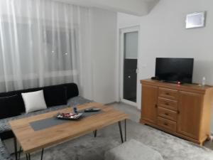 a living room with a couch and a television on a dresser at Apartman Velez in Nevesinje