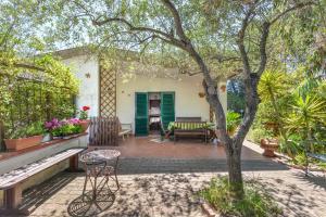 a patio with a table and chairs and a tree at Casa Neda in Procchio