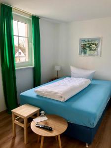 a bedroom with a blue bed and a table and a window at Pension "Strandhotel" in Vitte