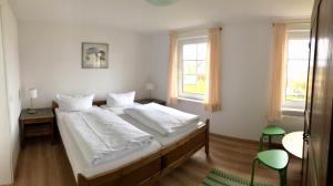 um quarto com uma cama com lençóis brancos e 2 janelas em Pension "Strandhotel" em Vitte