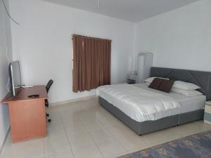 a bedroom with a bed and a desk and a television at HAPDESKO HOMESTAY in Batam Center
