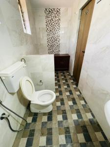 a bathroom with a toilet and a tiled floor at Colva Beach Samaira GuestHouse & Apartments in Colva