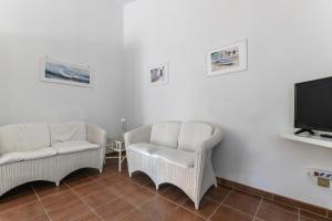 Una sala de estar con dos sillas y un televisor de pantalla plana. en Appartamento La Spiga, en Procchio