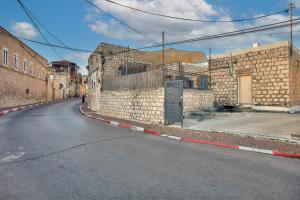 uma rua vazia ao lado de uma parede de tijolos em בראשית - סוויטות בוטיק בצפת העתיקה - Beresheet - Boutique Suites in the Old City em Safed