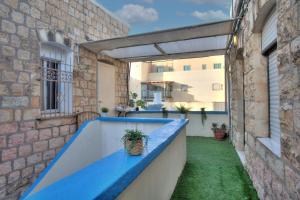 einen Außenbalkon mit einer blauen Bank und einem Gebäude in der Unterkunft בראשית - סוויטות בוטיק בצפת העתיקה - Beresheet - Boutique Suites in the Old City in Safed