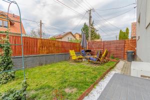 a backyard with chairs and an umbrella and a fence at Pannónia Szentendre in Szentendre