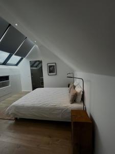 a white bedroom with a large bed and a window at Chez Arthur in Marche-en-Famenne