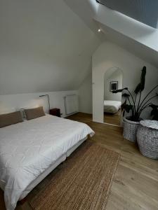 1 dormitorio con cama blanca y maceta en Chez Arthur, en Marche-en-Famenne
