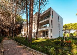 a white house with a brick walkway next to trees at Illyrian Elite Gjiri i Lalezit in Durrës